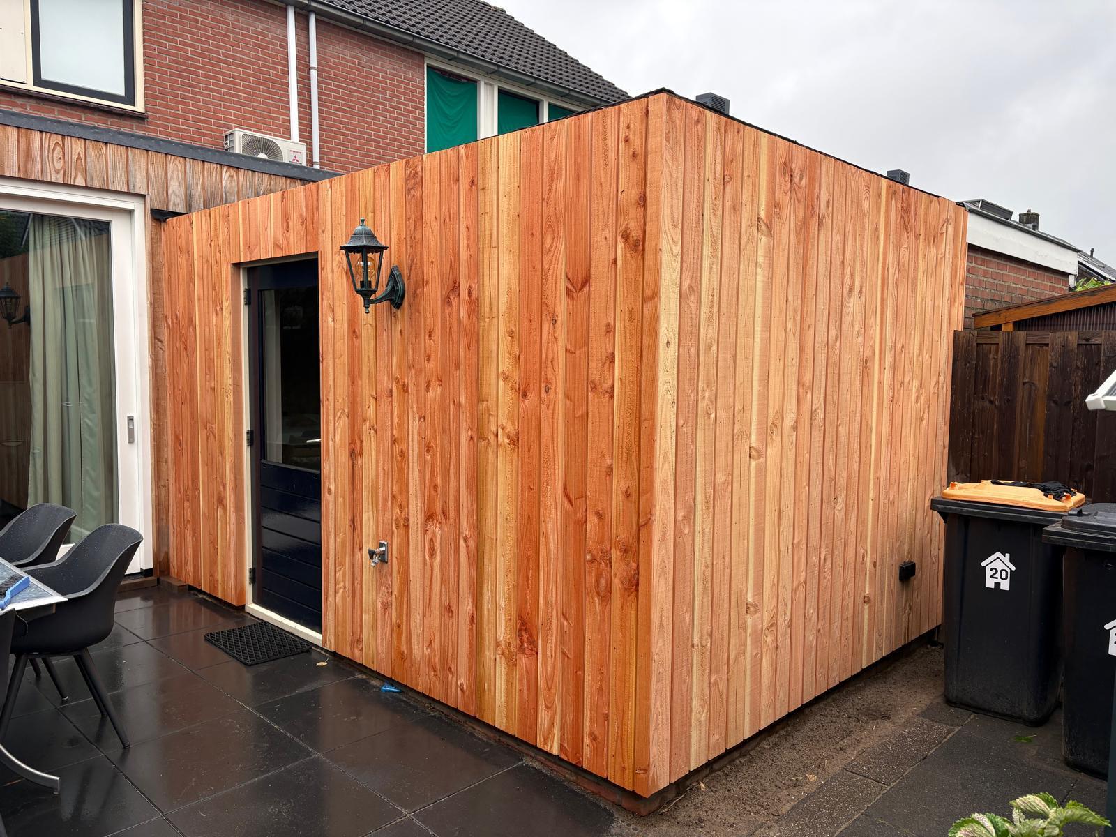 Aanbouw met verticale houten gevelbekleding aan de achterzijde van een woning