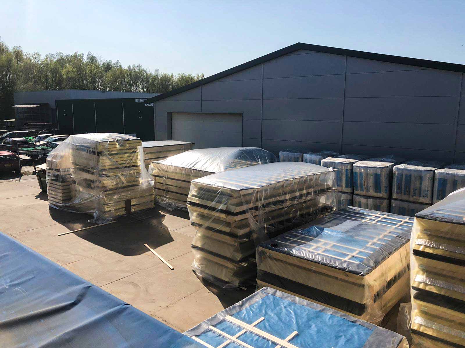 Ingepakte prefab elementen klaar voor transport op het buitenterrein voor de productiehal